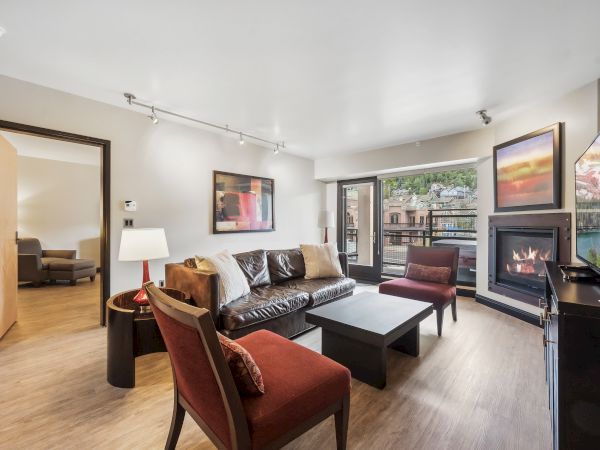 A modern living room with a sofa, chairs, coffee table, fireplace, and large windows offering a scenic view.