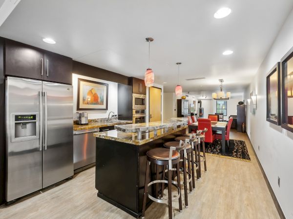 A modern kitchen with an island, bar stools, stainless steel appliances, and contemporary decor in a cozy, well-lit space.