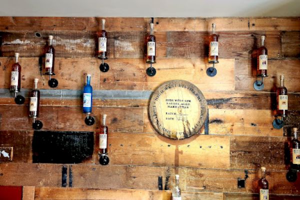 A wooden wall decorated with various bottles, a small clock, and signs.