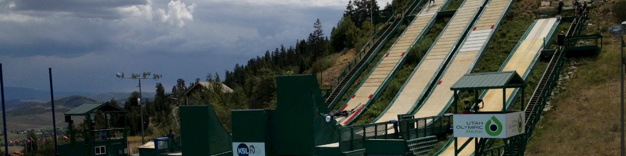 The image shows ski jumps with ramps leading into a pool, suggesting a training or recreational facility.