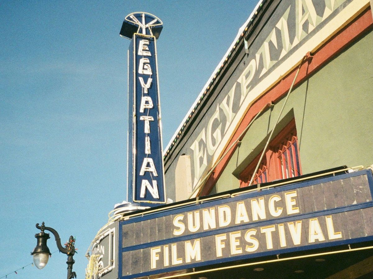 The image shows the Egyptian Theatre with a marquee advertising the Sundance Film Festival against a clear blue sky.