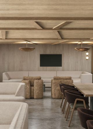 A modern lounge with beige sofas, wooden ceiling beams, pendant lights, and dining tables with dark chairs.