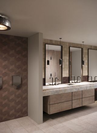A modern restroom with wall mirrors, multiple sinks on a stone counter, pendant lights, and ceiling fixtures over tiled walls.